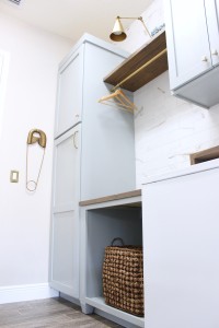 laundry room-diy-painted-cabinets-rustic-countertop-marble-wall-tile-gold-sconce-light-shelf-above-washer-dryer